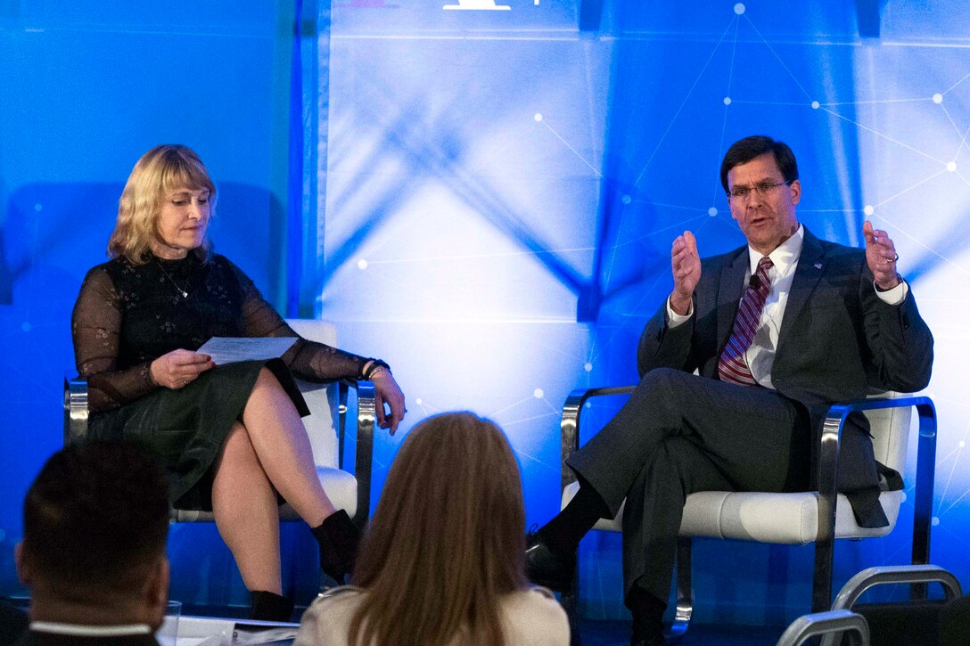 A man and woman sit near each other on a stage.
