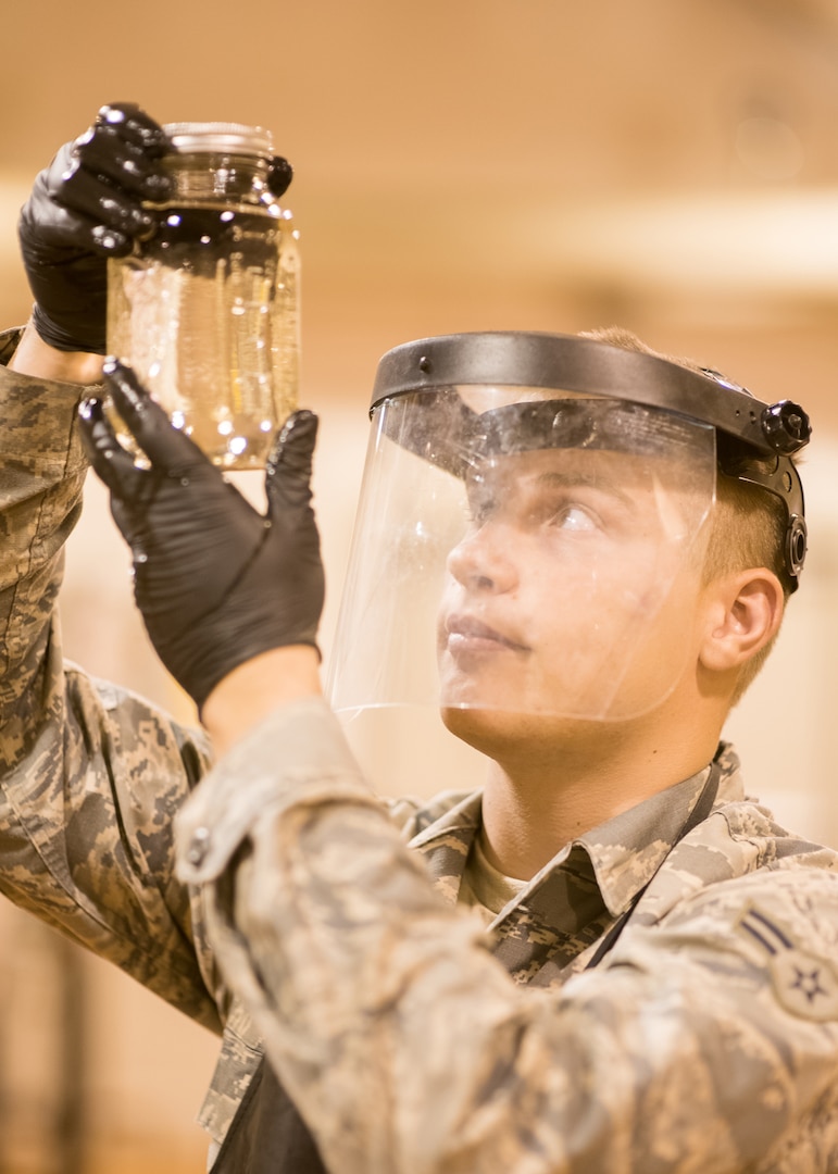 Airman 1st Class Austin Stepp, 436th Logistics Readiness Squadron fuels distribution operator, inspects a jet fuel sample for sediment and discoloration, Oct. 29, 2019, at Dover Air Force Base, Del. Fuel is inspected daily to ensure all aircraft get the cleanest fuel possible. (U.S. Air Force photo by Mauricio Campino)