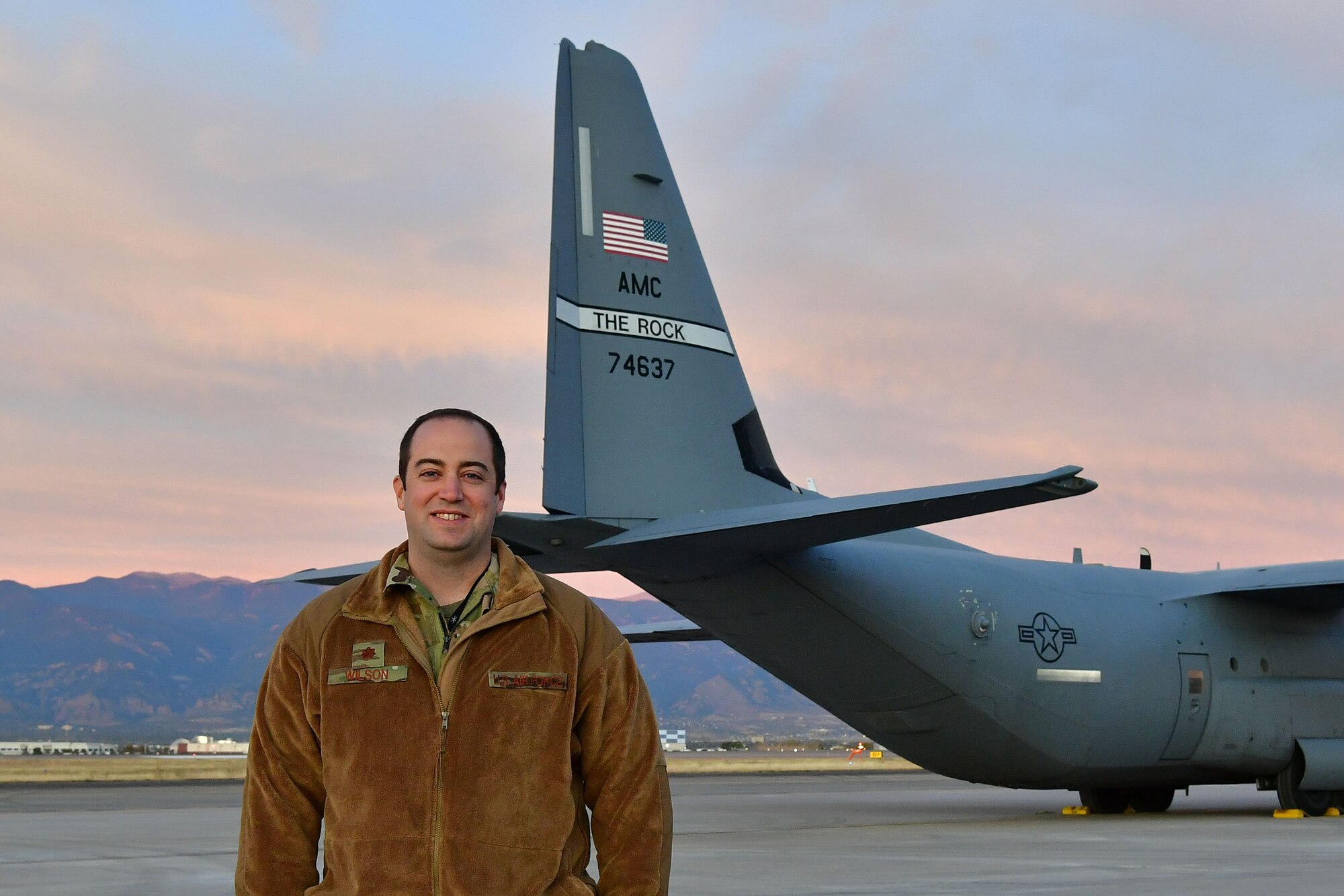 The assistant director of operations poses for a photo in front of a C-130 in Colorado.