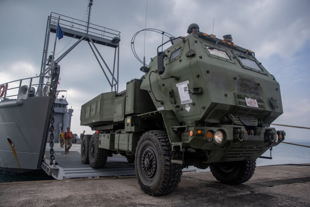 U.S. Marines with 12th Marine Regiment, 3rd Marine Division, and U.S. Soldiers with 97th Transportation Company, 10th Support Group, work together to quickly embark transportation vehicles and a High Mobility Artillery Rocket System on the U.S. Army Vessel Harpers Ferry (LCU-2022) during a joint service HIMARS embarkation training exercise in Kin, Okinawa, Japan, Oct. 31, 2019. This event marks the first time a Marine HIMARS was loaded on to an Army landing craft in the Indo-Pacific. Strategic mobility is key in the Indo-Pacific and the ability to transport the HIMARS over water is a vital capability that the 3rd Marine Division is now able to expand upon by partnering with the 10th Support Group. (U.S. Marine Corps photo by Lance Cpl. D’Angelo Yanez)