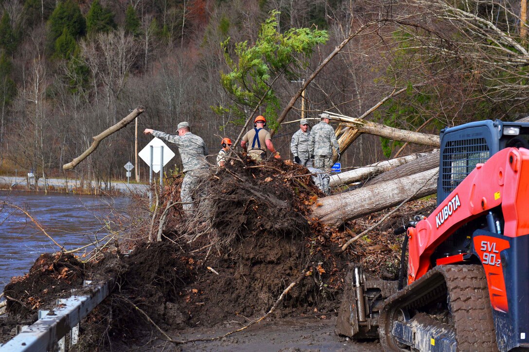 National Guard airmen clear debris from blocked road.