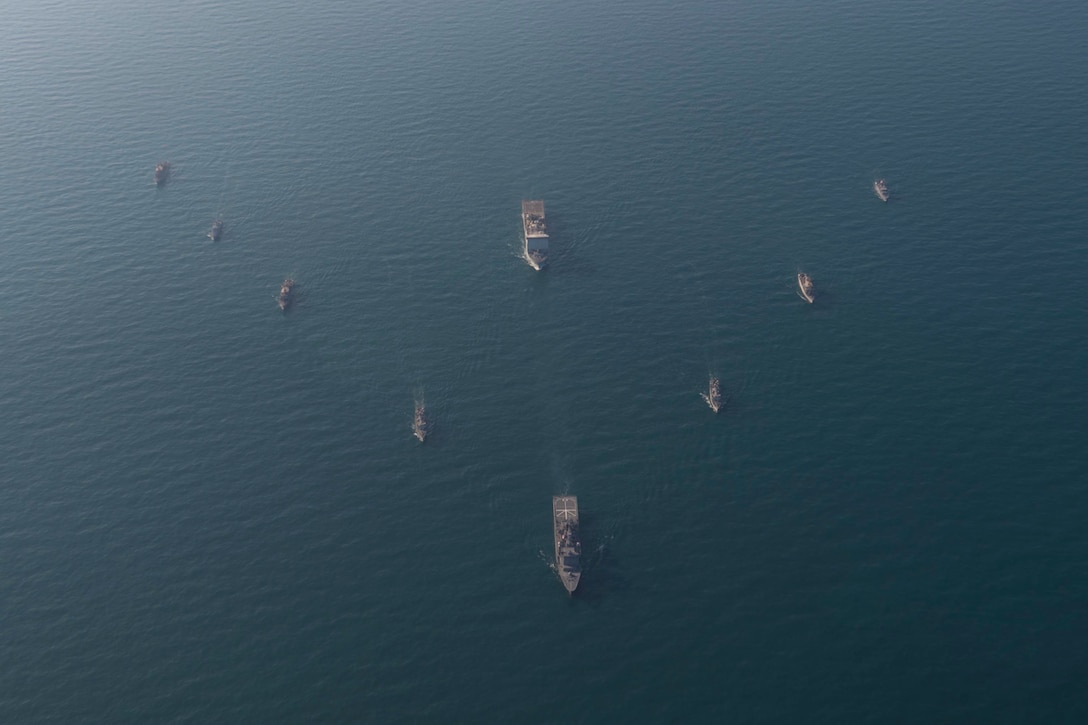 A group of ships sail in a V formation.