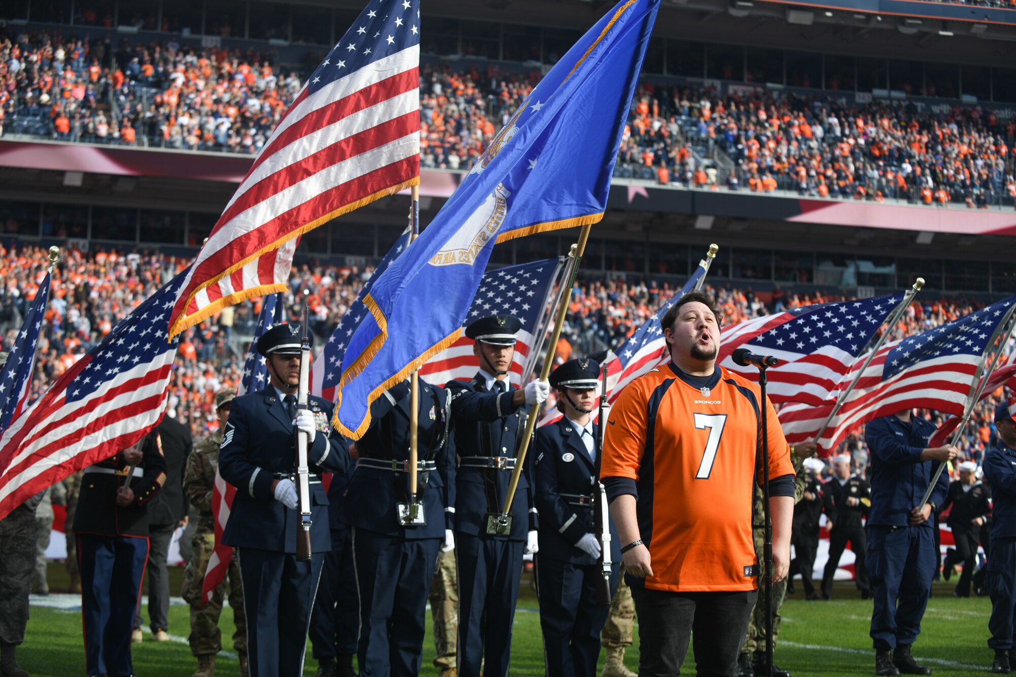 U.S. military service members stand at attention as Zach Kononov sings the national anthem, before the Denver Broncos Salute to Service game, at Empower Field at Mile High in Denver Nov. 3, 2019.