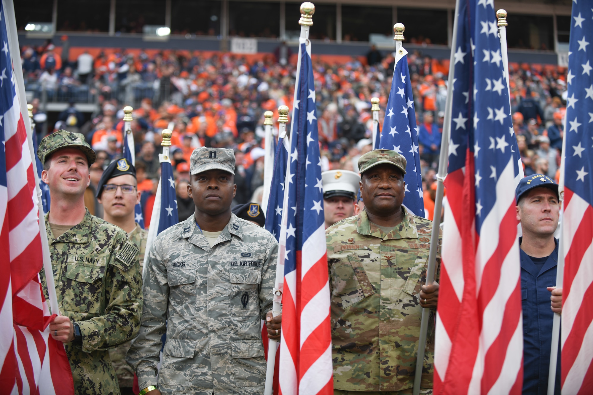 U.S. military service members hold American flags before the Denver Broncos Salute to Service game at Empower Field at Mile High in Denver, Nov. 3, 2019.