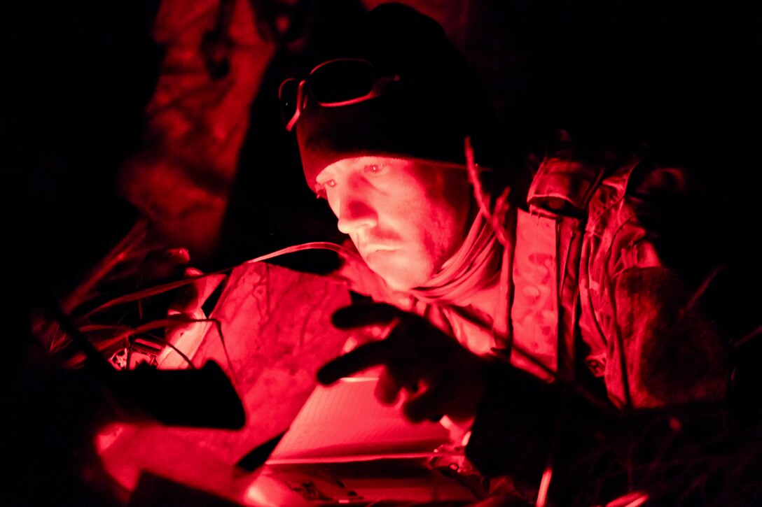 A soldier reads a map with a red light surrounding.