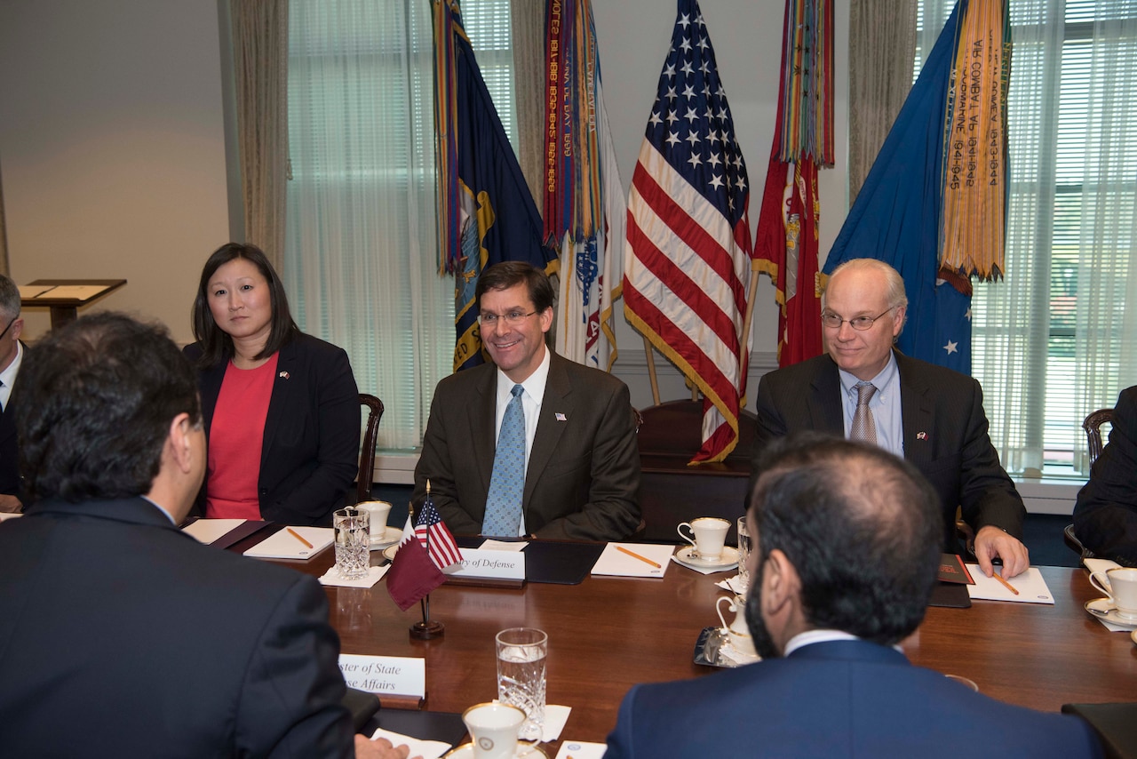 Defense Secretary Dr. Mark T. Esper, center, smiles in a conference room.