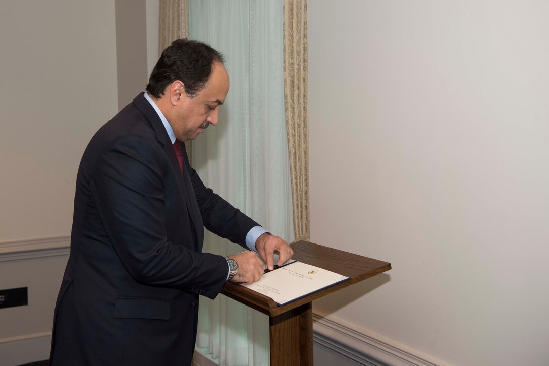 Qatar defense minister signs book.