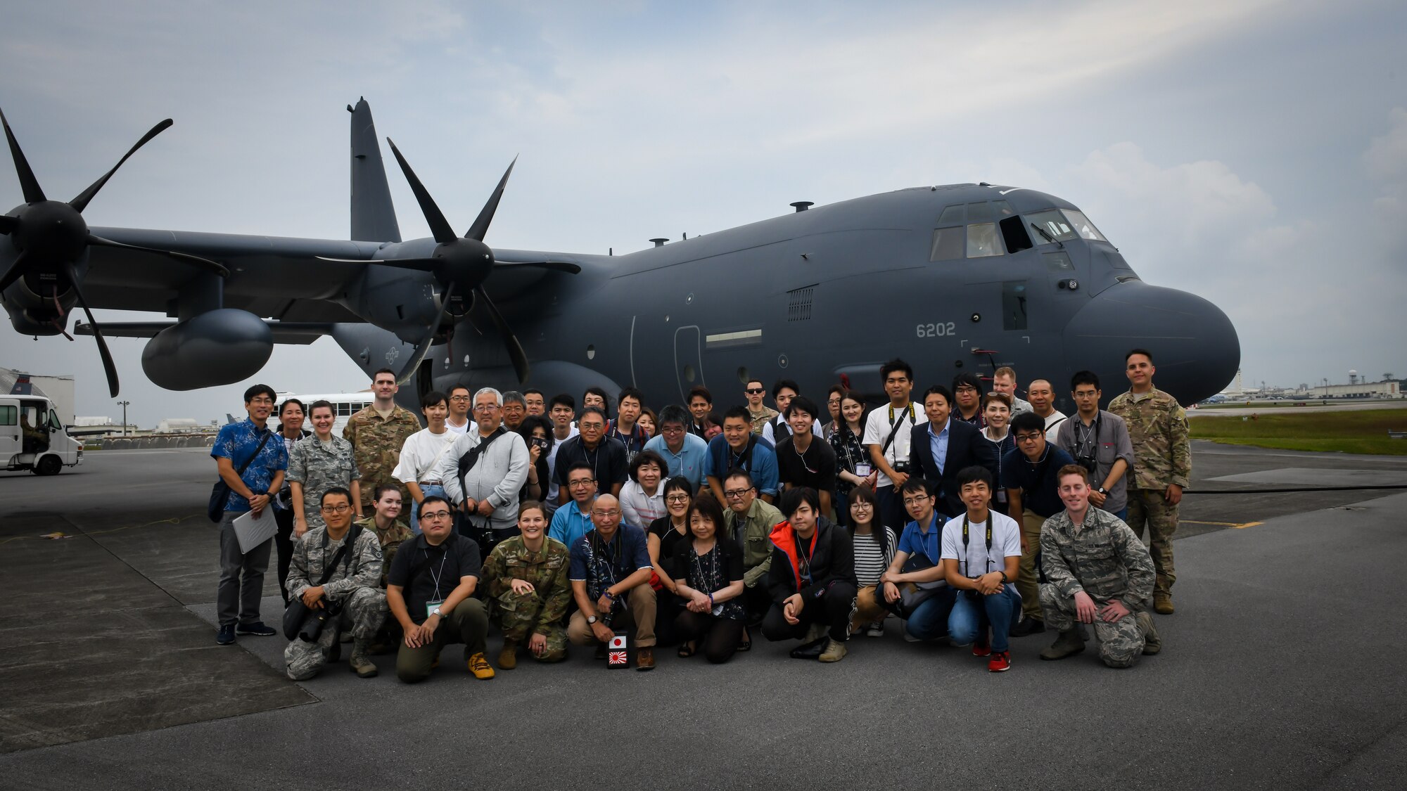 Members from 18th Wing Public Affairs and Twitter Tour visitors pose for a photo in front of an MC-130J Commando II on Kadena Air Base, Japan, Nov. 4, 2019. During the tour, visitors learned about the 18th Wing mission, security forces partnerships with the Okinawa Prefectural Police, how the base maintains good stewardship of the environment, and Kadena-based aircraft. (U.S. Air Force photo by Staff Sgt. Benjamin Raughton)