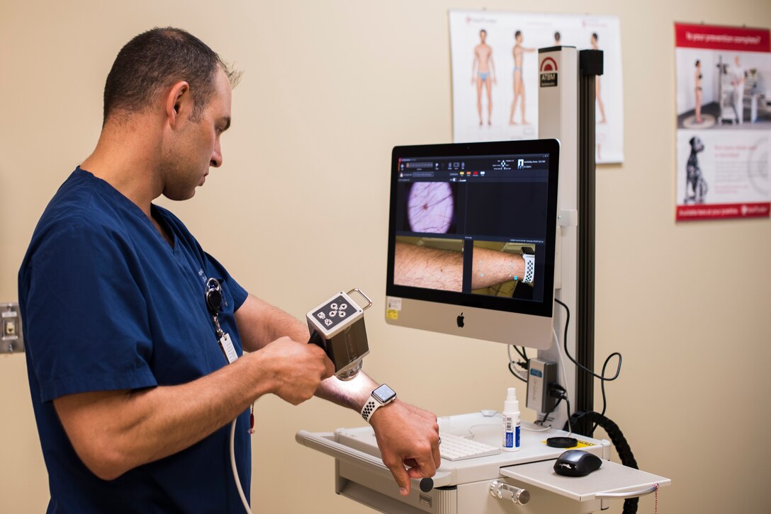 Maj. Thomas Beachkofsky, 6th Health Care Operations Squadron dermatologist, uses a body scanner microscope to take a picture of a spot on his arm at MacDill Air Force Base, Fla., Oct. 30, 2019. A new software upgrade allows a complex algorithm to analyze an image captured with a camera and rate the severity of the spot for a dermatologist to review. (U.S. Air Force photo by Senior Airman Adam R. Shanks)