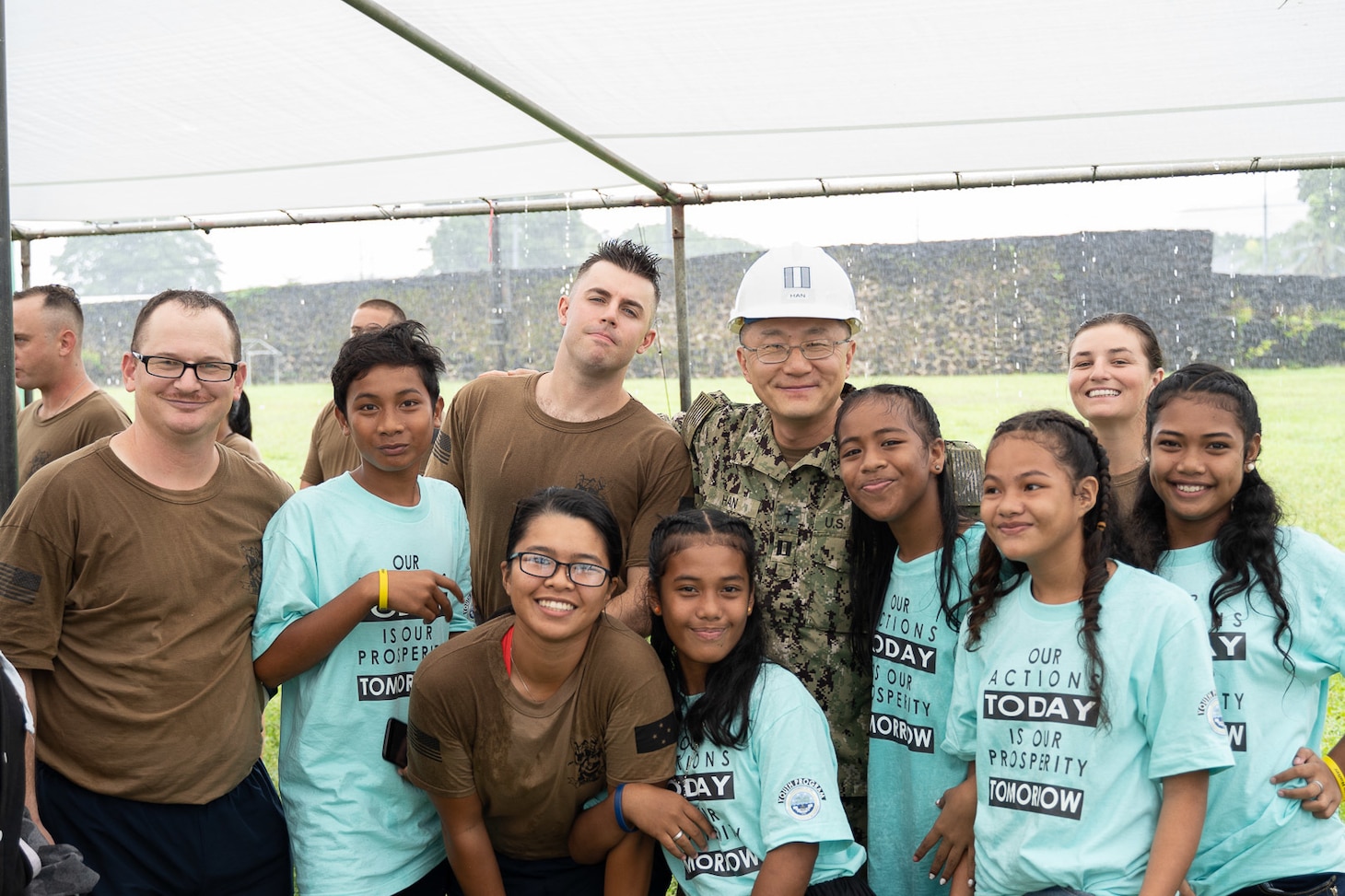 191104-N-WA745-1024 KOLONIA, Pohnpei (Nov. 4, 2019) Seabees deployed with Naval Mobile Construction Battalion (NCMB) 5’s Detail Pohnpei and members of the Sokehs Youth Choir pose for a photograph outside the Kolonia Gymnasium during the Federated States of Micronesia Independence Day celebration in Pohnpei Nov. 4.  The Seabees are providing humanitarian aid to the local community by finishing a medical facility, Nan U Dispensary, and performing renovations to multiple schools across the island. NMCB-5 is deployed across the Indo-Pacific region conducting high-quality construction to support U.S. and partner nations to strengthen partnerships, deter aggression, and enable expeditionary logistics and naval power projection.