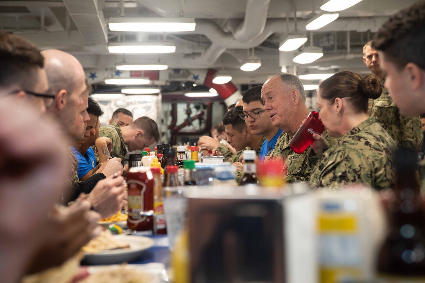 Rear Adm. Brent W. Scott, the U.S. Navy Chief of Chaplains, talks and eats with Sailors in the aft mess decks of the Navy’s forward-deployed aircraft carrier, USS Ronald Reagan (CVN 76). Ronald Reagan, the flagship of Carrier Strike Group 5, provides a combat-ready force that protects and defends the collective maritime interests of its allies and partners in the Indo-Pacific region.