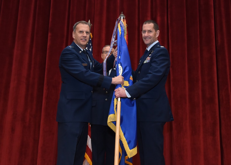 Maj. Gen. Randall A. Ogden, 4th Air Force commander, passes the 911th Airlift Wing guidon to the incoming commander, Col. John F. Robinson, during an assumption of command ceremony at Moon Area Middle School in Coraopolis, Pennsylvania, Nov. 2, 2019.