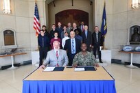 Dean of the Volgenau School of Engineering at George Mason University (GMU) Dr. Kenneth Ball (left, seated); Naval Surface Warfare Center Carderock Division Technical Director Larry Tarasek (center, standing); and Commanding Officer Capt. Cedric McNeal (right, seated) pose in front of other Carderock employees and GMU students on Nov. 1, 2019. Ball and McNeal signed an Educational Partnership Agreement (EPA), ensuring years of partnership, collaboration and the promotion of practical, real-world applications of STEM programs and education. (U.S. Navy photo by Neubar Kamalian/Released)