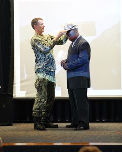 Shipyard Commander Capt. Kai Torkelson places Code 900P Martrail Parker's hardhat upon him in honor of his completion of the Executive Development Program.