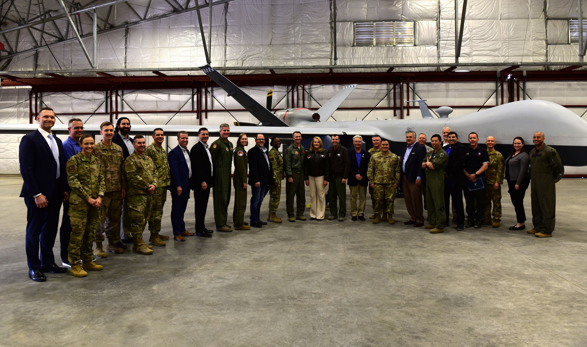 Members of Creech Air Force Base and the Las Vegas community stand in a line for a group photo near an MQ-9 Reaper