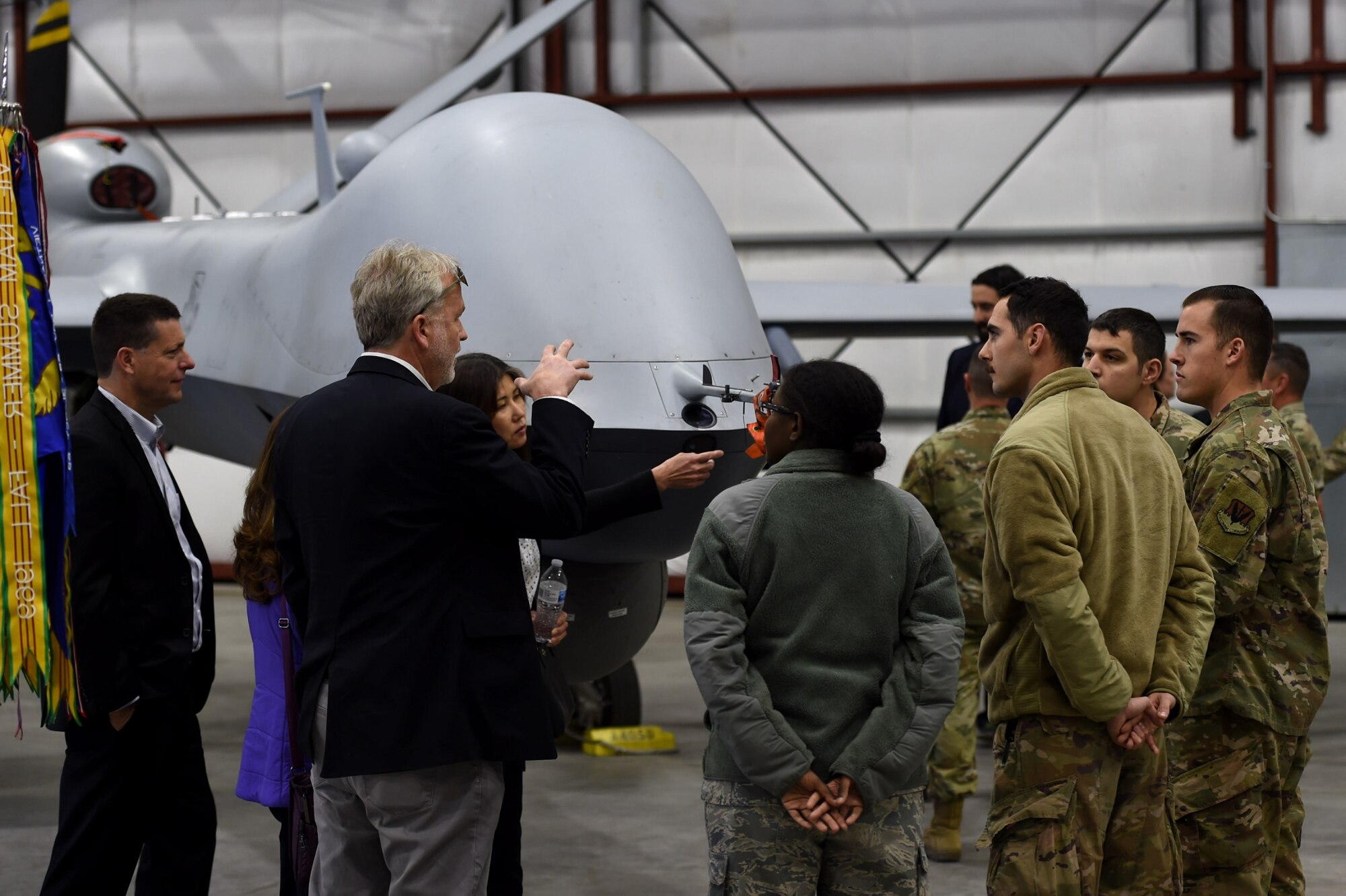 Members of the 432nd Wing and the Las Vegas community stand in a hangar near an MQ-9 Reaper