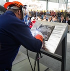 Ingalls Shipbuilding welder James Ellis welds Ship Sponsors Ruby Lucas and Catherine B. Reynolds’ initials into a steel plate during a keel authentication ceremony for the future USS Jack H. Lucas (DDG 125) at Huntington Ingalls Industries Pascagoula shipyard Nov. 7, 2019.