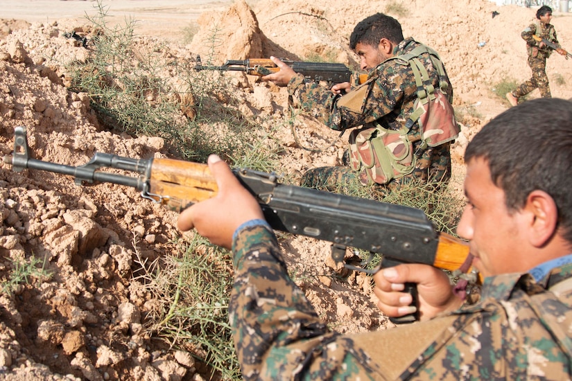 A uniformed service member aims his rifle.