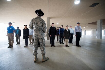 Civic leaders were surprised during the Airmen Training Center tour as U.S. Air Force Tech. Sgt. Lewis Christopher (center), 319th Training Squadron, military training instructor, orders them to get in formation for a crash course on marching, facing movements, and dormitory life, Nov. 7, 2019, at Joint Base San Antonio-Lackland, Texas.