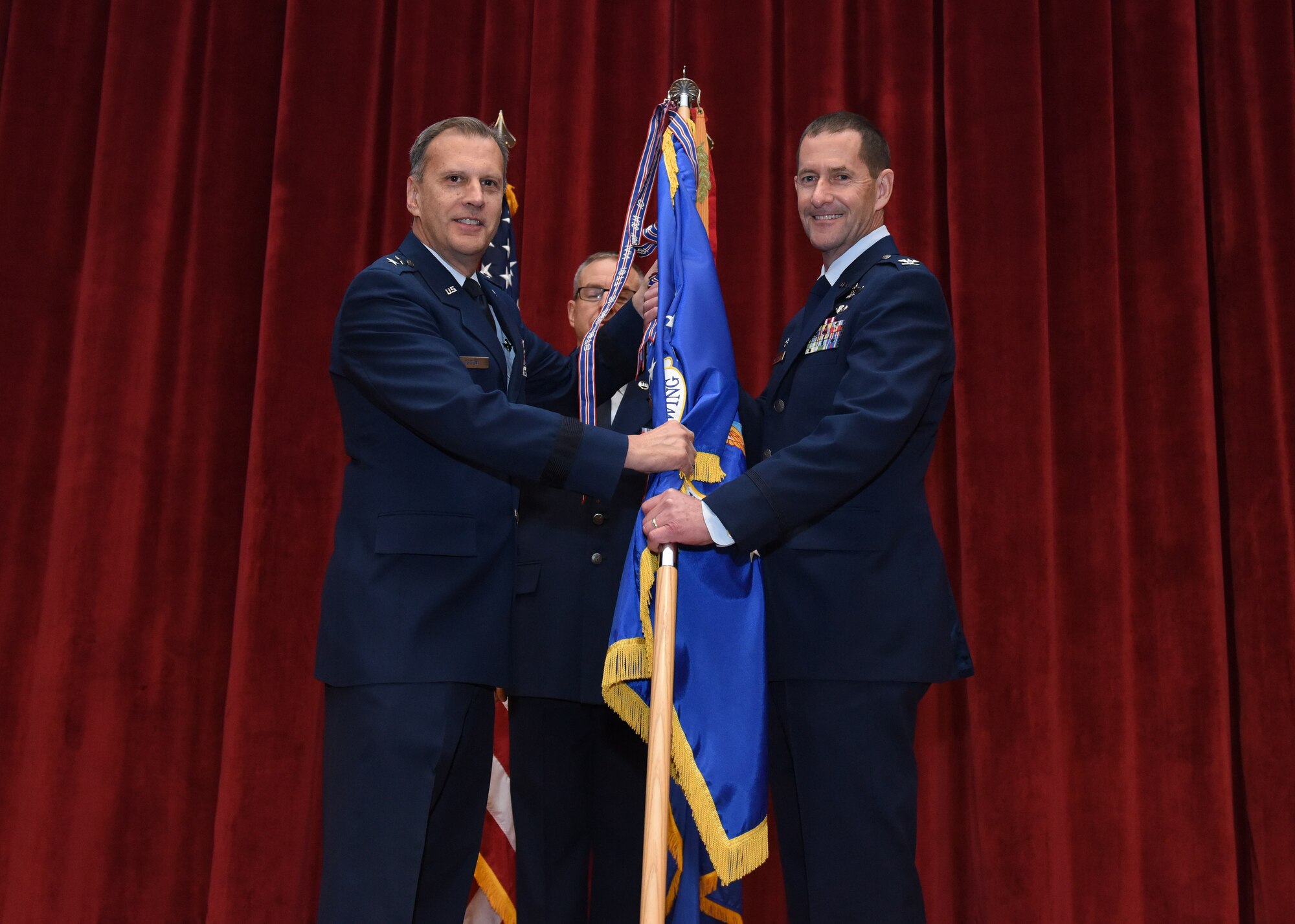 Maj. Gen. Randall A. Ogden, 4th Air Force commander, passes the 911th Airlift Wing guidon to the incoming commander, Col. John F. Robinson, during an assumption of command ceremony at Moon Area Middle School in Coraopolis, Pennsylvania, Nov. 2, 2019.