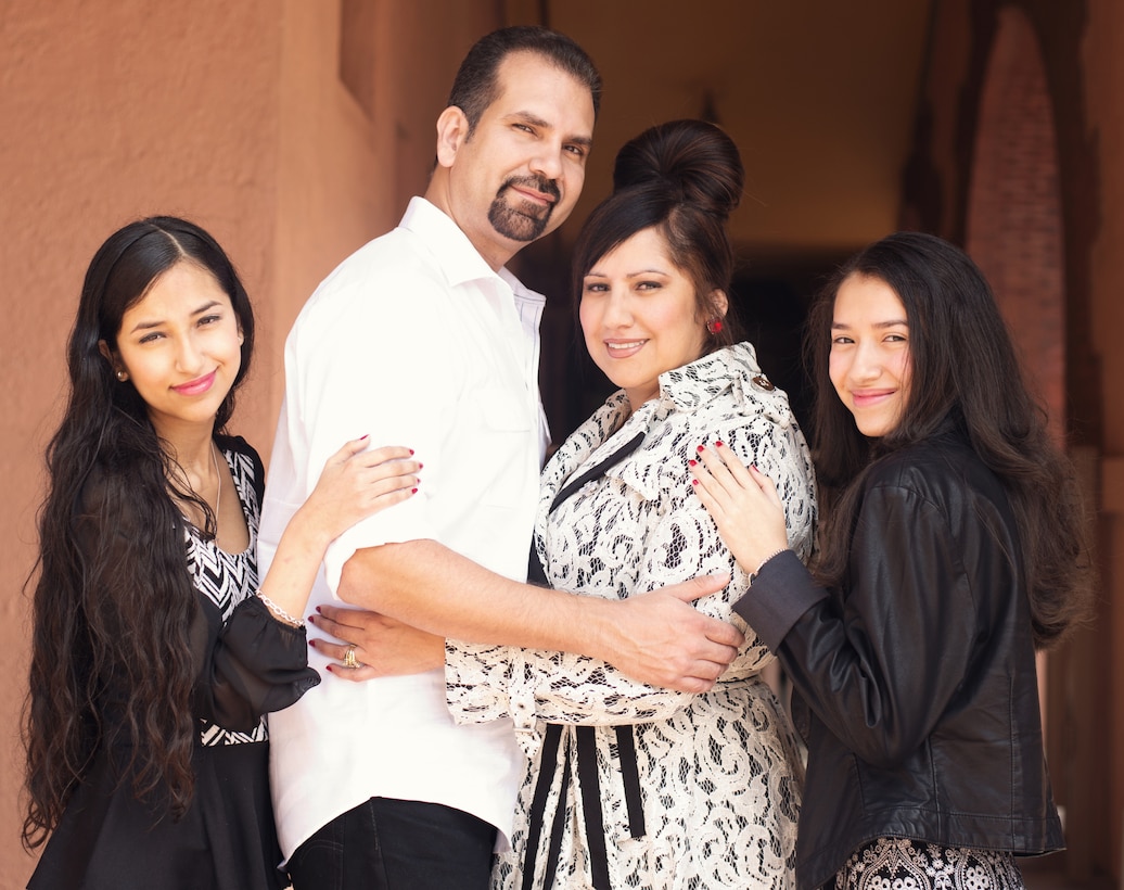 A family poses together with a mother, father and two daughters.