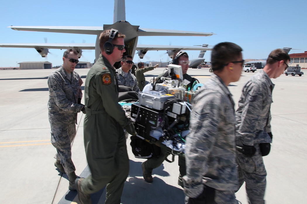 During an engine-running offload, a litter-carry team moves a simulated critically ill patient out of a C-130J Super Hercules to a waiting ambulance bus during 349th Air Mobility Wing Air Force Specialty Code training June 6, 2015, at Travis Air Force Base, Calif. In preparation for the training, the 349th Aeromedical Evacuation Squadron transformed the four-engine tactical transport into a flying hospital. In turn, the CCATT teams from the 60th Surgical Operations Squadron and the 349th Aeromedical Staging Squadron established onboard what was essentially a portable intensive care unit dedicated to one very ill, simulated, "patient." The C-130 was from the California Air National Guard's 146th Airlift Wing, Channel Islands Air National Guard Station, California. (U.S. Air Force photo/Lt. Col. Robert Couse-Baker/Released)