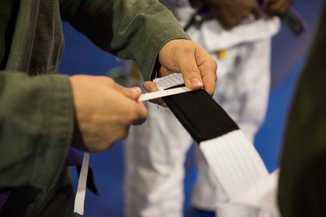 U.S. Air Force Staff Sgt. Christian Brancato, a Brazilian Jiu-Jitsu coach, ties a stripe to one of his students’ belts during a class Nov. 7, 2019, at Incirlik Air Base, Turkey. In the martial arts world, practitioner’s ranks are coded by the color of their belts, while the stripes on those belts signify tiers within those ranks. (U.S. Air Force photo by Staff Sgt. Joshua Magbanua)