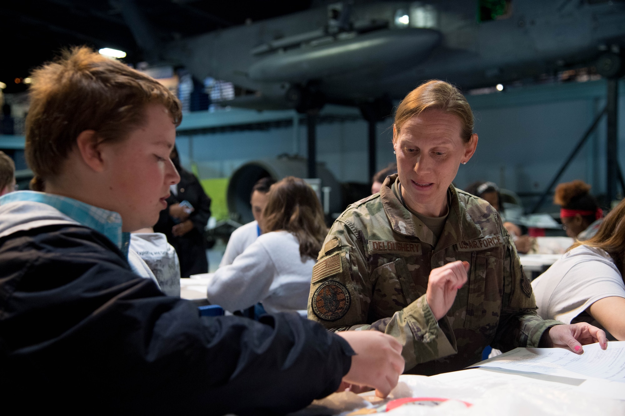 Col. Cheryl Deloughery, deputy chief of civil engineering at Air Force Reserve Command, assists a local high school student with assembling a model rocket ship out of paper and other office supplies during a science, technology, engineering, art and science event hosted by AFRC and the Society of American Military Engineers at the Museum of Aviation at Robins Air Force Base, Georgia, Nov. 8, 2019. Students were asked to create a model rocket that launch to a designated area using air pressure while holding enough pennies to represent crew and cargo.