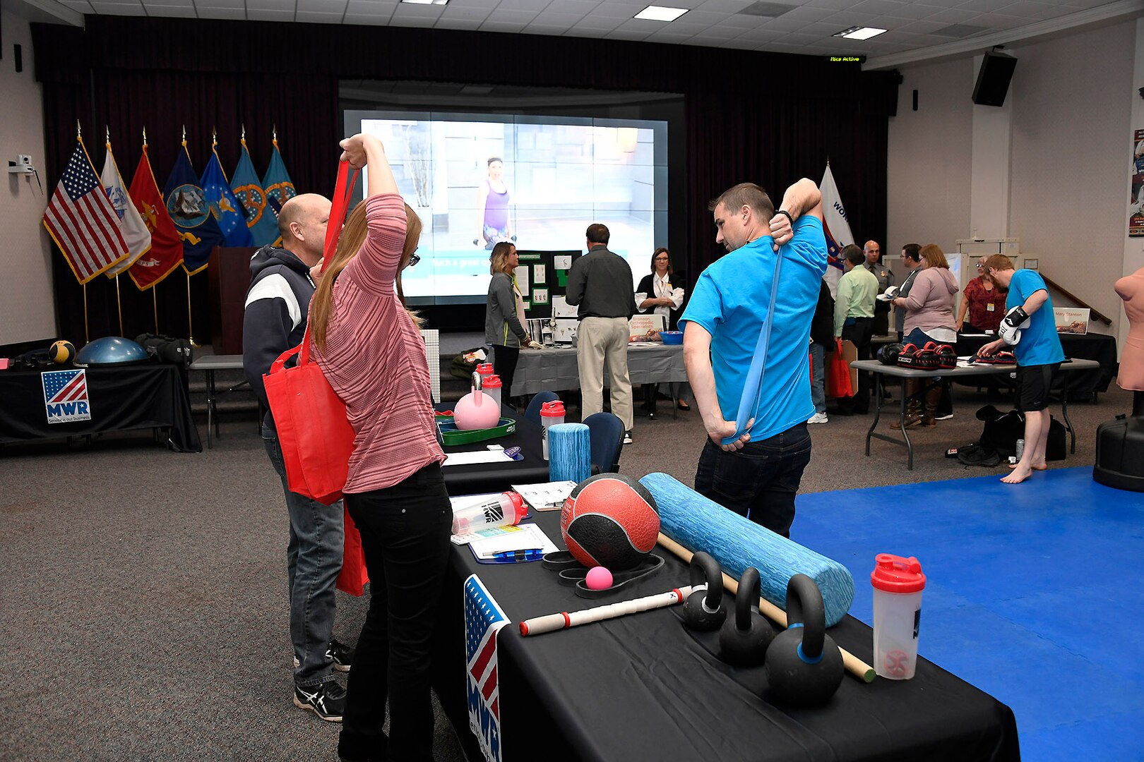 MWR Personal Trainer Daniel Roberts demonstrates uses for elastic bands on display with training equipment.