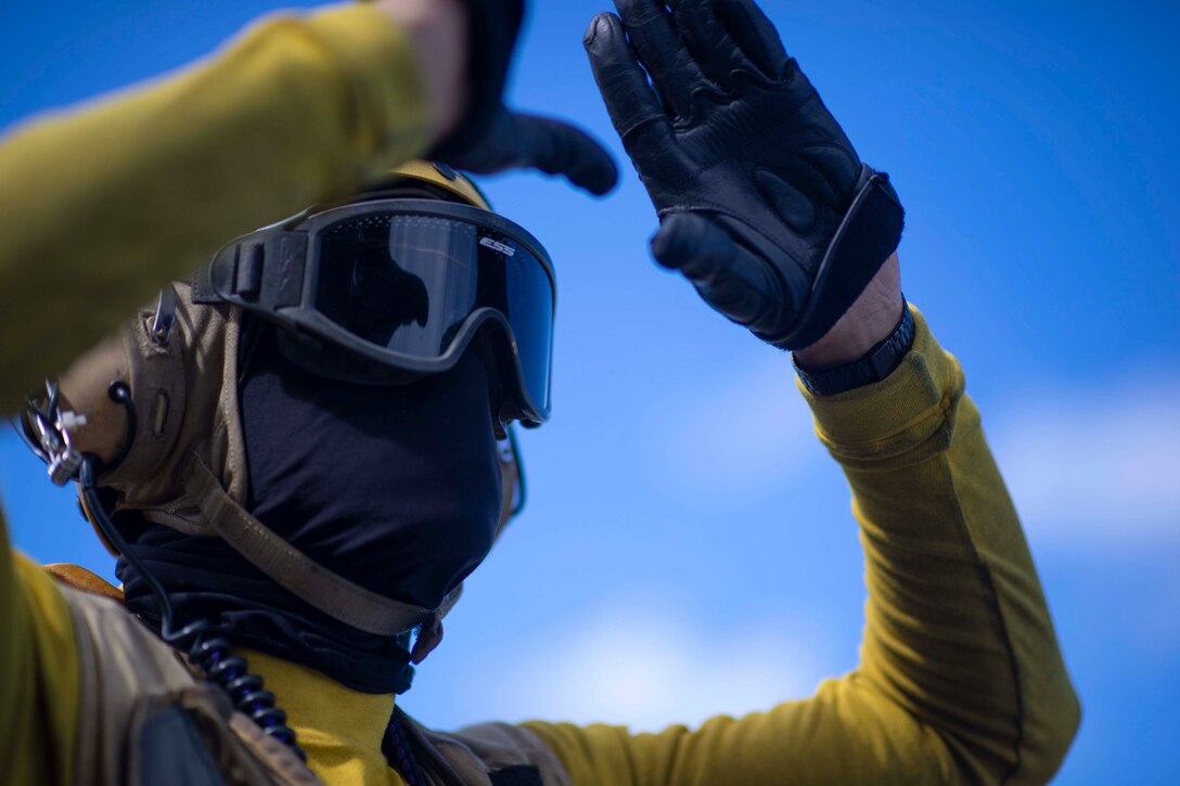 A sailor holds his hands above his head forming a triangle.