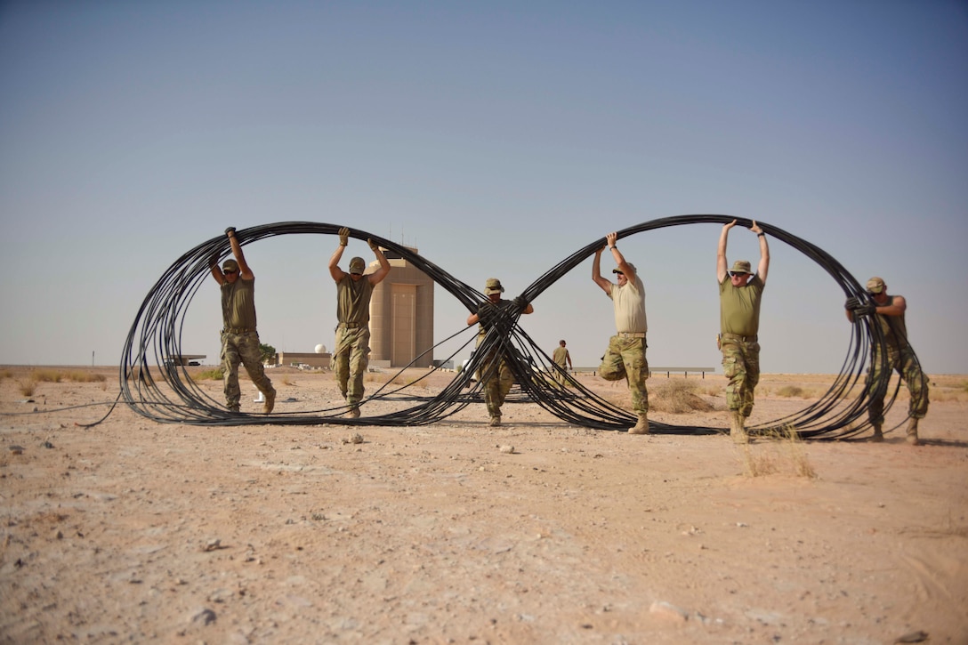 A group of airman move a cable.