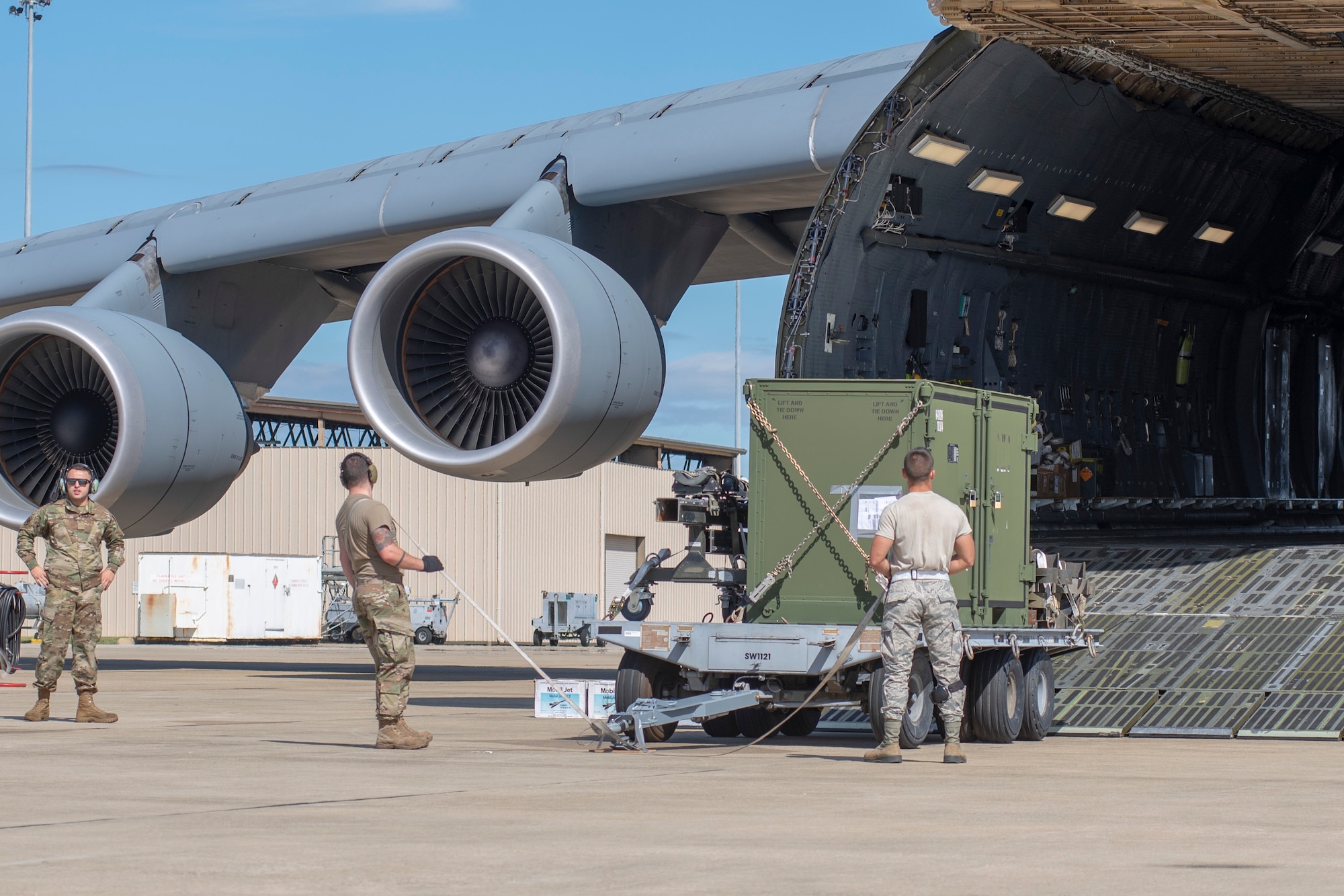 From left, U.S. Air Force Airman 1st Class Michael Shelton, 9th Airlift Squadron loadmaster, Senior Airman Jacob Guy, 20th Logistics Readiness Squadron (LRS) small air terminal deployment instructor, and Airman 1st Class Justen McCallister, 20th LRS aerial transportation specialist, wait to begin loading cargo aboard a C-5M Galaxy on the flightline at Shaw Air Force Base, South Carolina, Oct. 24, 2019.