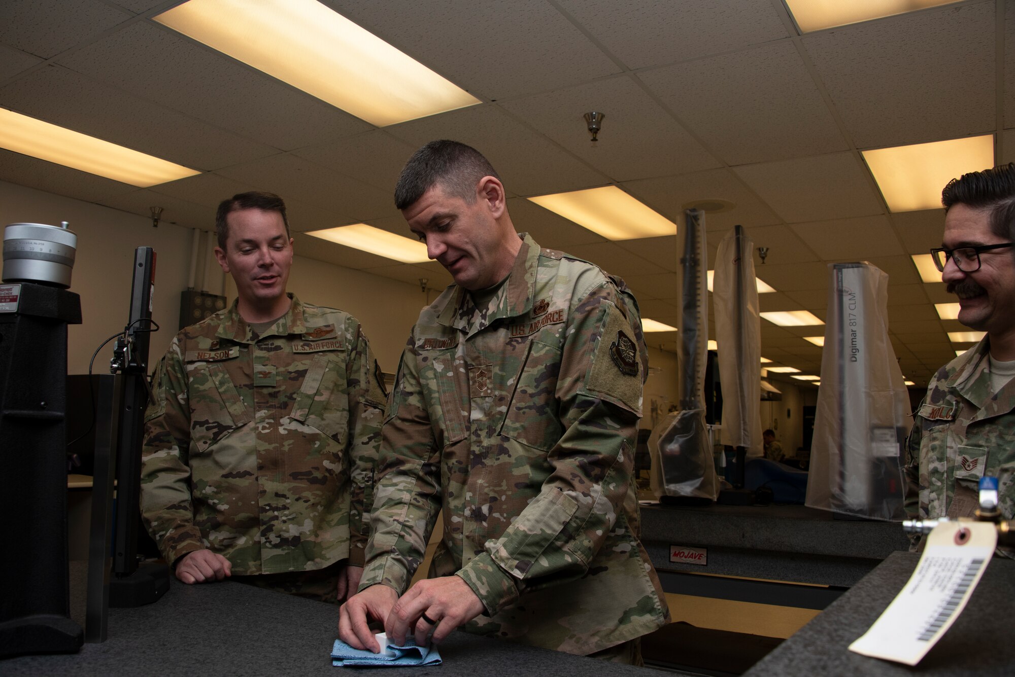 U.S. Air Force Chief Master Sgt. Derek Crowder, center, 60th Air Mobility Wing command chief, works with gauge blocks during a Leadership Rounds visit inside the 60th Maintenance Squadron Precision Measurement Equipment Laboratory while Col. Jeff Nelson, left, 60th AMW commander and Staff Sgt. Vincenzo Kupilow, right, 60th MXS physical dimensional craftsman, look on Nov. 1, 2019 at Travis Air Force Base, California. The PMEL team is responsible for ensuring the accuracy of test equipment for 255 work centers. The Leadership Rounds program provides 60th AMW leadership an opportunity to interact with Airmen to get a detailed view of each mission performed at Travis AFB. (U.S. Air Force photo by Tech. Sgt. James Hodgman)