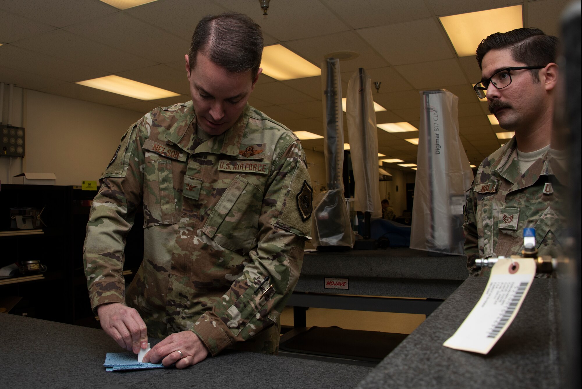 U.S. Air Force Col. Jeff Nelson, left, 60th Air Mobility Wing commander, works with gauge blocks inside the 60th Maintenance Squadron Precision Measurement Equipment Laboratory Nov. 1, 2019 while Staff Sgt. Vincenzo Kupilow, right, 60th MXS physical dimensional craftsman, looks on during a Leadership Rounds visit at Travis Air Force Base, California. The PMEL team is responsible for ensuring the accuracy of test equipment for 255 work centers. The Leadership Rounds program provides 60th AMW leadership an opportunity to interact with Airmen to get a detailed view of each mission performed at Travis AFB. (U.S. Air Force photo by Tech. Sgt. James Hodgman)