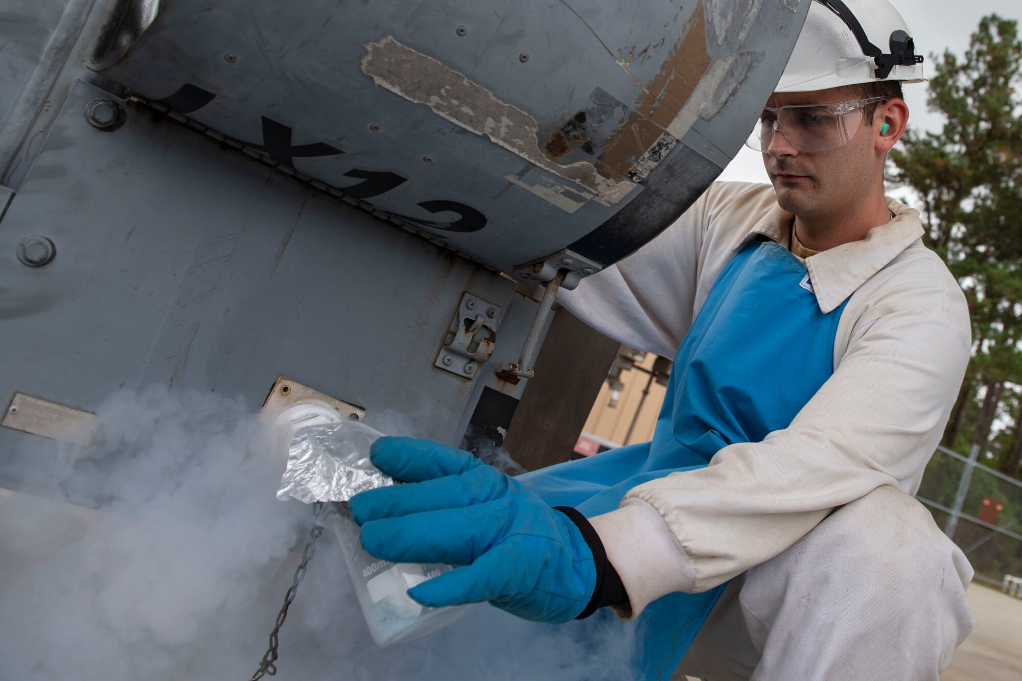 A photo of an Airman collecting a sample of liquid oxygen