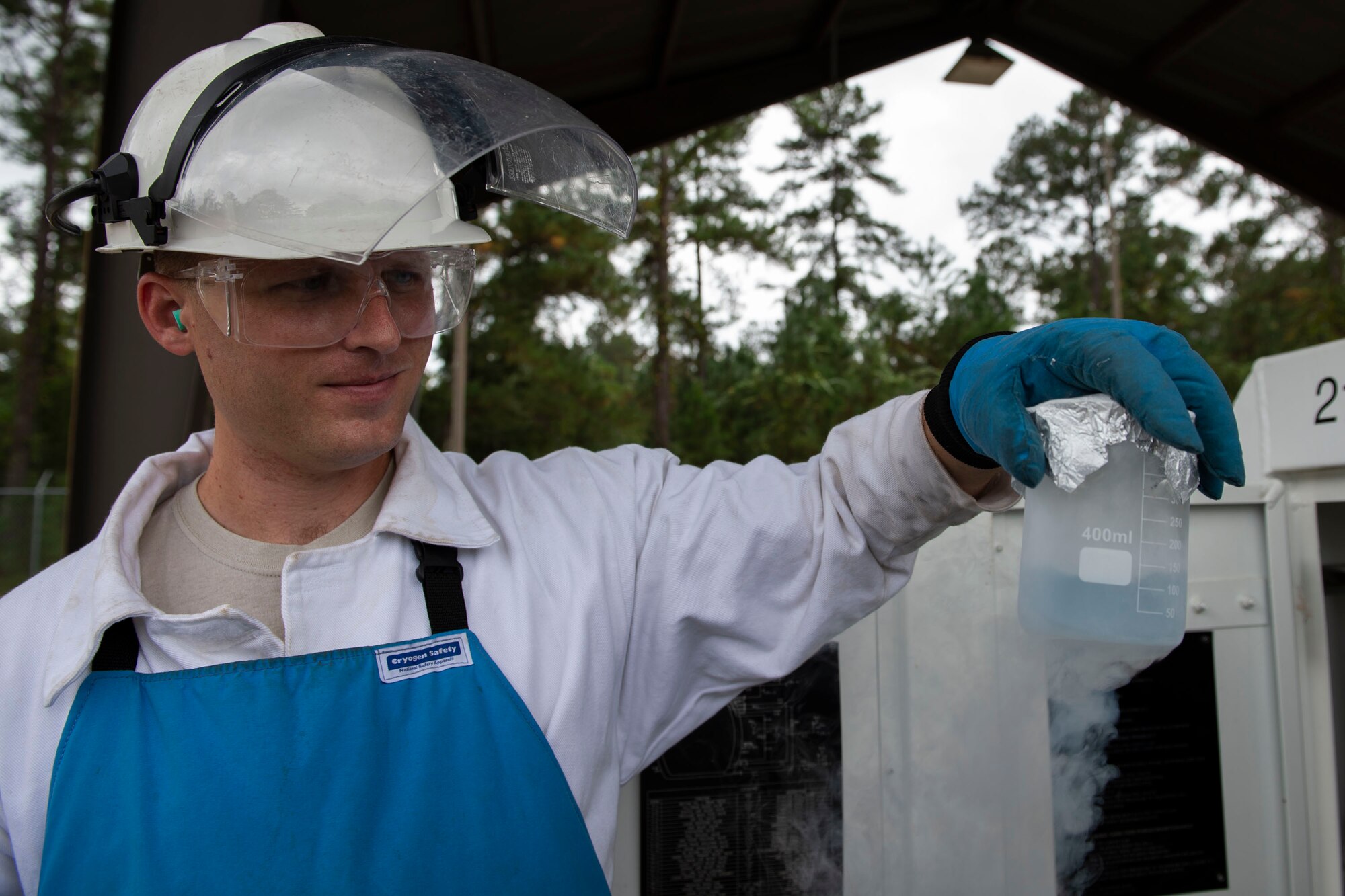 A photo of an Airman observing a sample of liquid oxygen