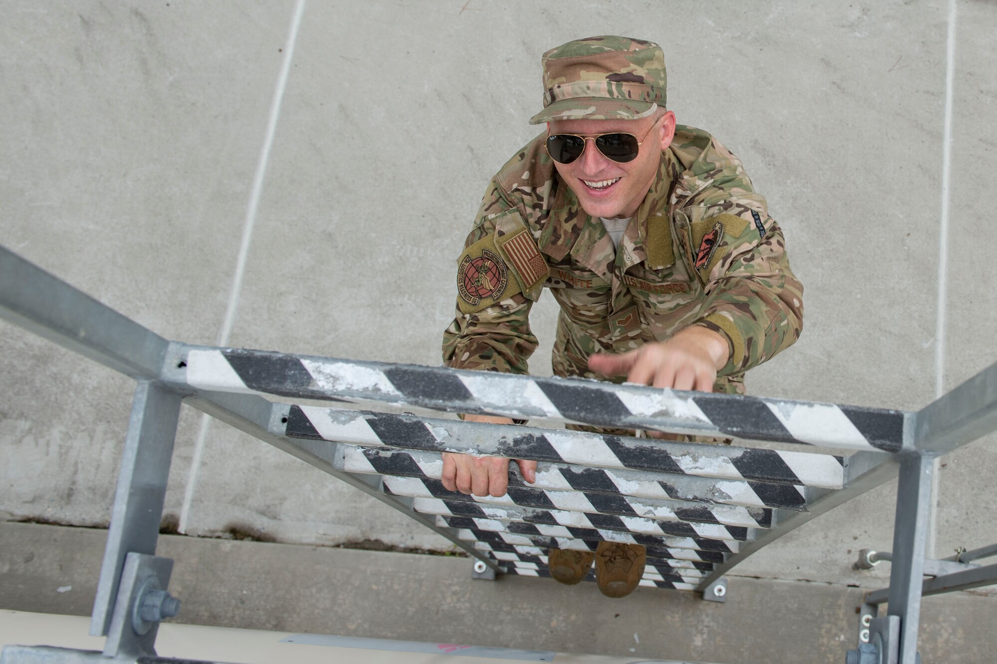 A photo of an Airman climbing a ladder on a fuel tank