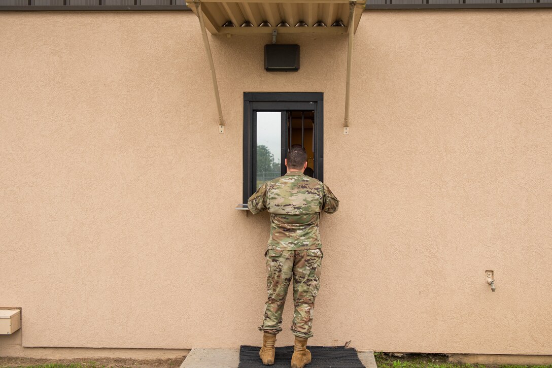 An Airman assigned to the 23d Maintenance Squadron talks with a munitions controller through the customer service window Nov. 7, 2019, at Moody Air Force Base, Ga. The Munitions Flight Systems Division is responsible for maintaining the security of ‘Ammo Country’ as well as tracking munitions and orders from around Moody. Airmen assigned to this division control security gates, escort visitors and communicate with flying squadrons to determine munitions needs. (U.S. Air Force photo by Airman Elijah M. Dority)