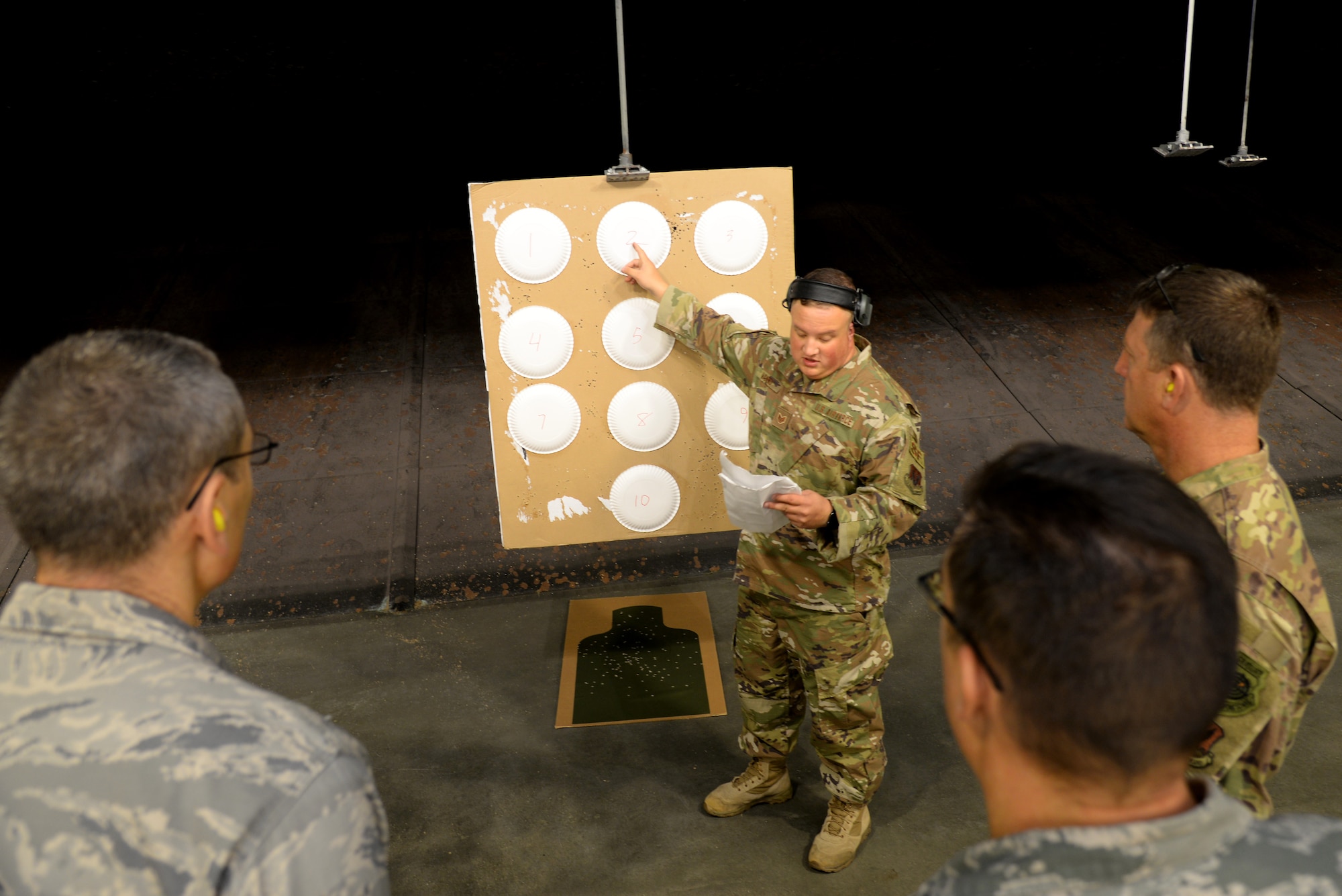 A picture of U.S. Air Force Staff Sgt. Dylan Manno, 177th Fighter Wing Security Forces Squadron combat arms trainee, points at paper targets at a firing range.