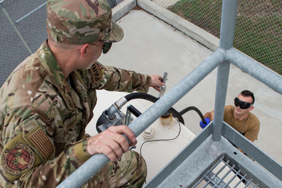 Staff Sgt. Bryan White, right, 23d Logistics Readiness Squadron (LRS) fuels facilities NCO in charge, hands a hose to Senior Airman Gavin Rees, 23d LRS fuels facilities technician Oct. 30, 2019, at Moody Air Force Base, Ga. The 23d LRS fuels facilities is responsible for maintaining facilities, product purity, storage and accountability. Fuels facilities Airmen maintain the base service station by performing routine checks on the operating valves, fuel tanks and service station parts. (U.S. Air Force photo by Airman Azaria E. Foster)