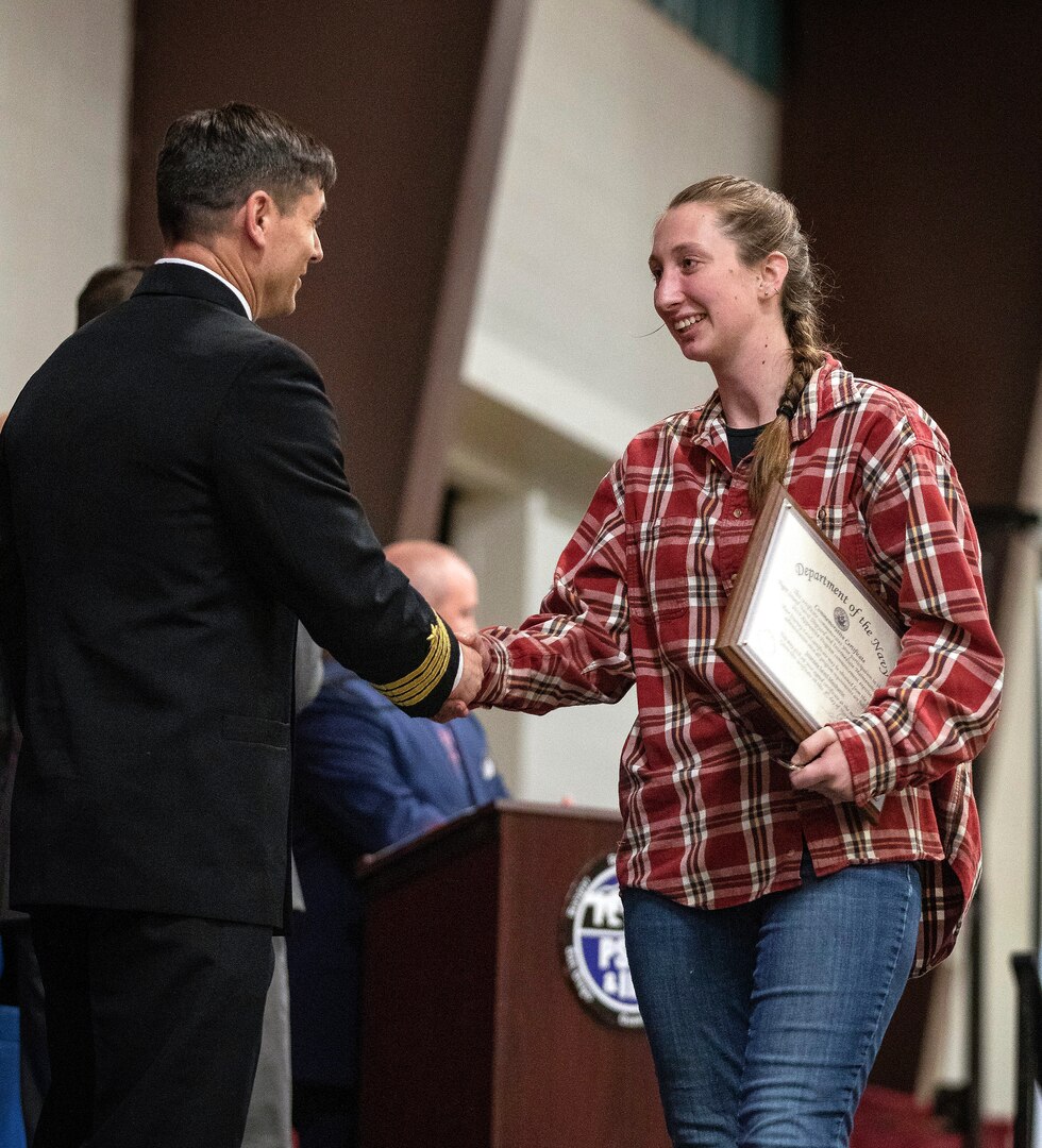 PSNS & IMF Operations officer Capt. Joshua Crinklaw, left, congratulates Apprentice of the Year awardee Nikole Starks after she received her graduation certificate during 2019 PSNS & IMF Apprentice Graduation ceremony Friday, Nov. 8 at the Kitsap County Fairgrounds Kitsap Sun Pavilion.