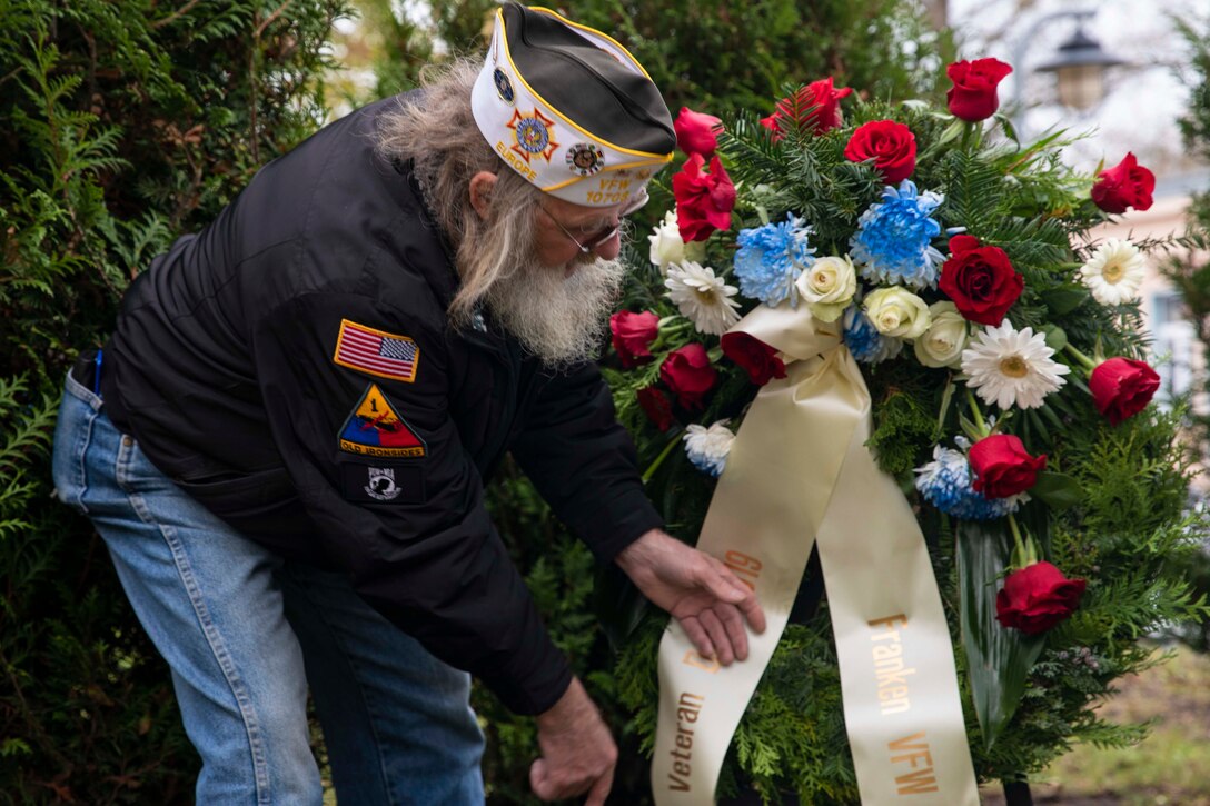A man places a wreath on a stand.