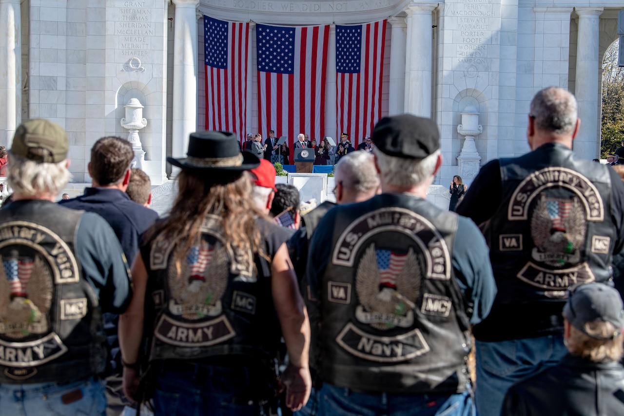 A group of service members in a large crowd look toward Vice President Mike Pence on stage.