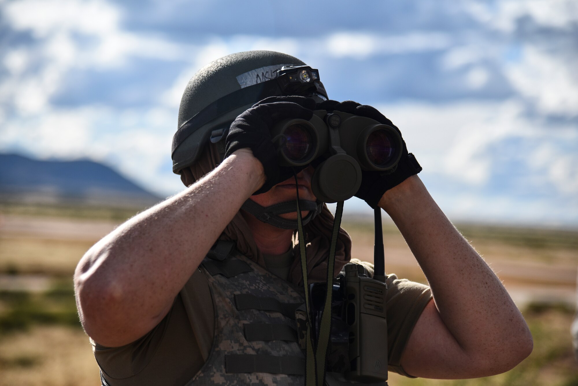 A photo of an airman with binoculars on look out.