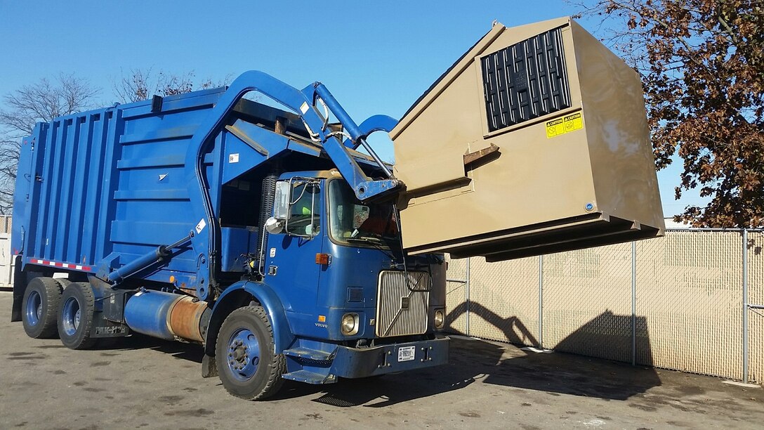 Ken Watkins, a motor vehicle operator, lifts a recycling container into the top of his EZ Packer which was recently purchased in Alaska. The EZ Packer saves time and money with its quick loading capabilities. (U.S Air Force photo/Gene Barnett)