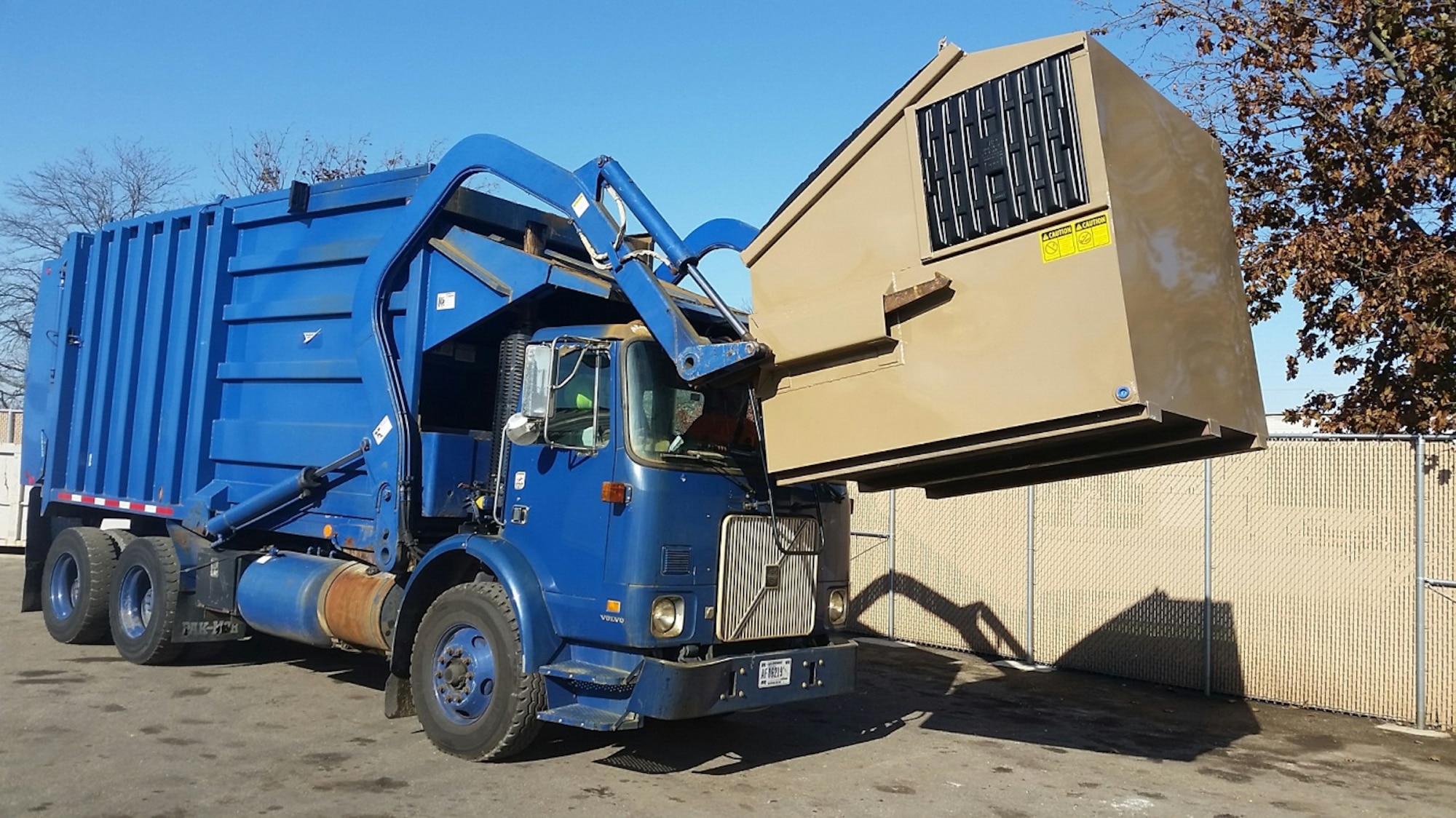 Ken Watkins, a motor vehicle operator, lifts a recycling container into the top of his EZ Packer which was recently purchased in Alaska. The EZ Packer saves time and money with its quick loading capabilities. (U.S Air Force photo/Gene Barnett)