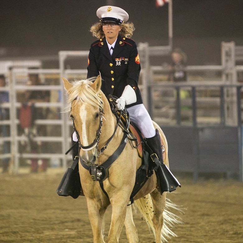 A Marine in formal dress rides a horse at a rodeo.