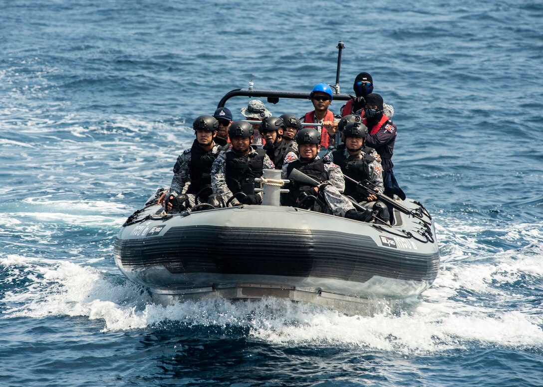 A small inflatable boat carries several sailors to a training vessel for a training exercise.