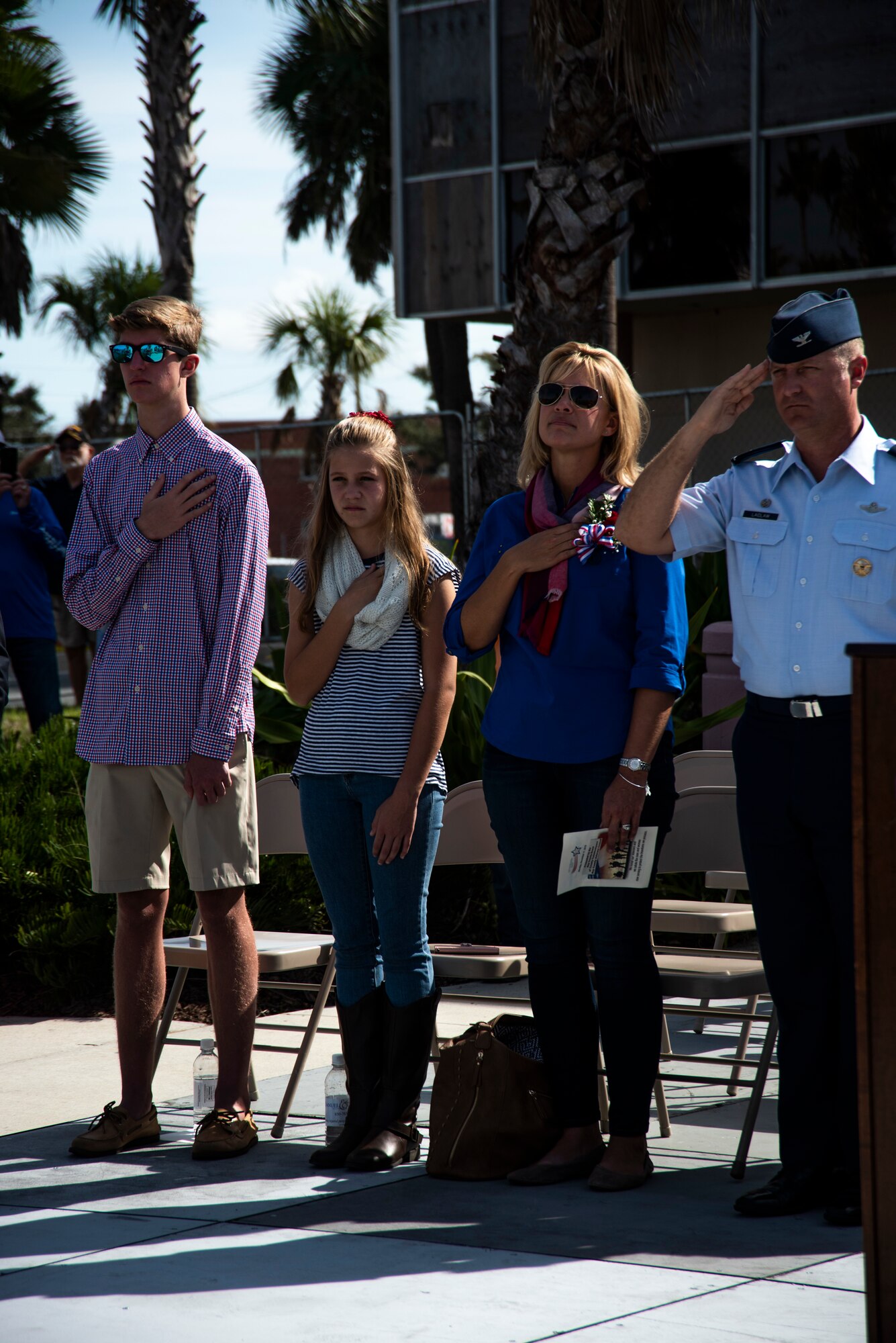 Col. Brian Laidlaw, 325th Fighter Wing commander, salutes the United States flag during the National Anthem and his family hold their hands over their hearts at the annual Veterans Day parade celebration and wreath laying ceremony on Nov. 11, 2019, at Panama City, Florida. The annual event celebrated those who served in the past and to honor the sacrifices made by the service member as well as their families, both at home and abroad. During the ceremony, Laidlaw highlighted the dedication families made as they supported their loved ones' service. Laidlaw identified that the military is a family business because families support the nation's defense as well. Laidlaw was accompanied by his wife Samantha, daughter Taylor and son Braden. (U.S. Air Force photo by Staff Sgt. Magen M. Reeves)