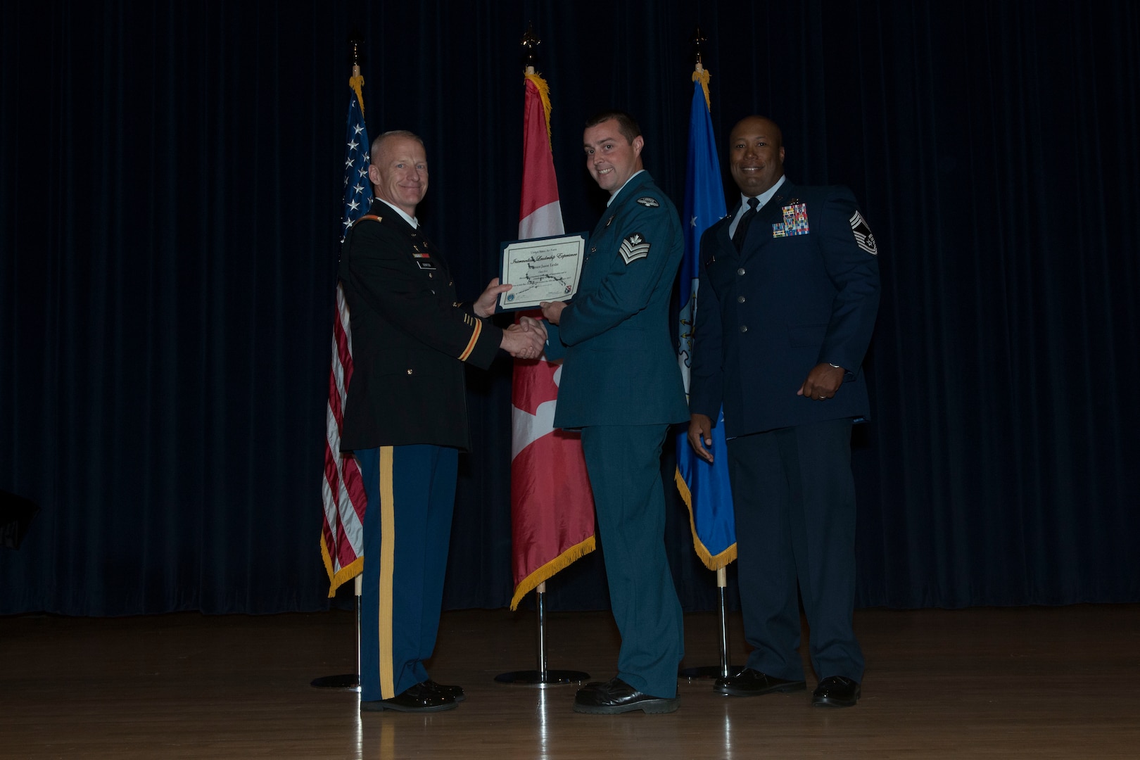Sgt Jason Leslie (center) receives his Non-Commissioned Officer Academy certificate at Elmendorf Professional Military Education Center at Joint Base Elmendorf-Richardson in Alaska.